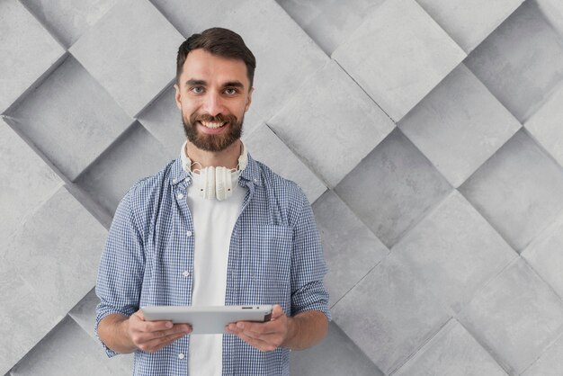 Hombre joven sonriente que sostiene la maqueta de la tableta