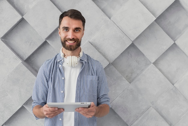 Hombre joven sonriente que sostiene la maqueta de la tableta