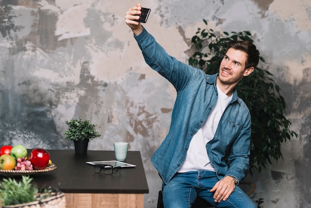 Foto gratuita hombre joven sonriente que toma selfie de teléfono móvil