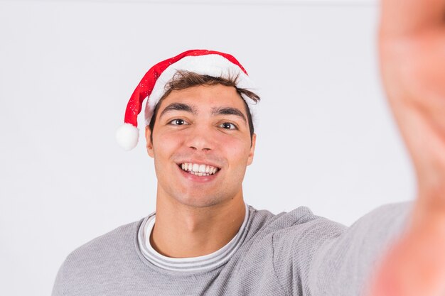 Hombre joven sonriente en sombrero de la Navidad