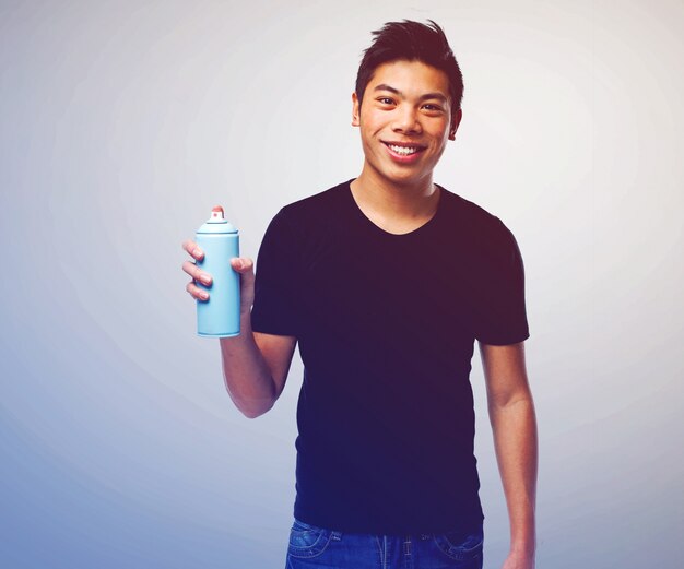 Hombre joven sonriente sujetando un aerosol