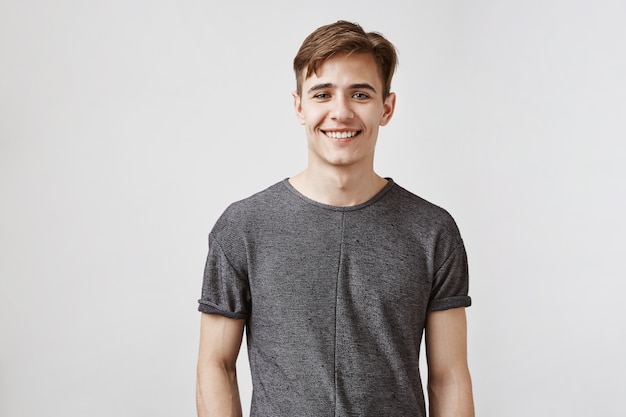 Hombre joven con una sonrisa encantadora y ojos azules posando