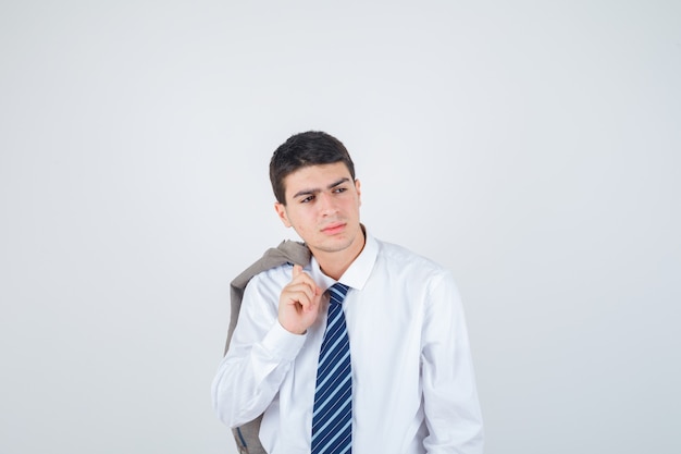 Hombre joven sosteniendo la chaqueta sobre el hombro con camisa blanca y corbata