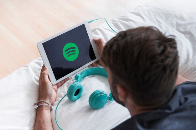 Hombre joven sosteniendo dispositivo moderno con la app de spotify