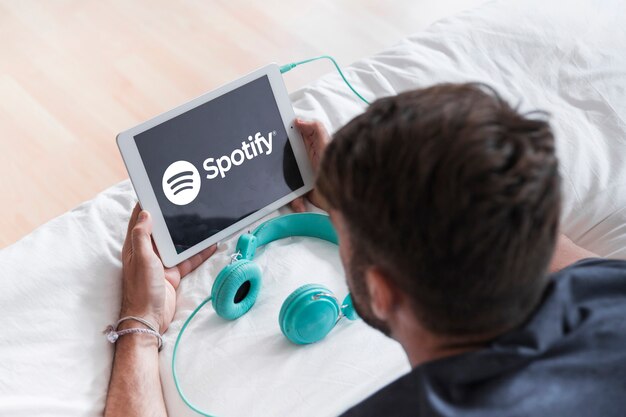 Hombre joven sosteniendo dispositivo moderno con la app de spotify