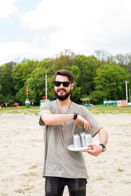 Hombre joven sosteniendo latas de cerveza