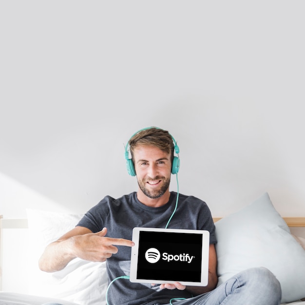 Foto gratuita hombre joven sosteniendo tablet con la app de spotify