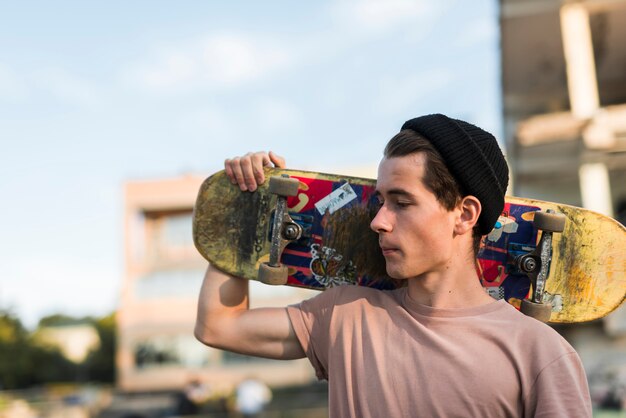 Foto gratuita hombre joven sujetando patineta