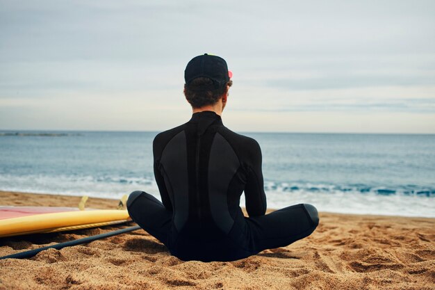 Hombre joven surfista en la playa con gorra