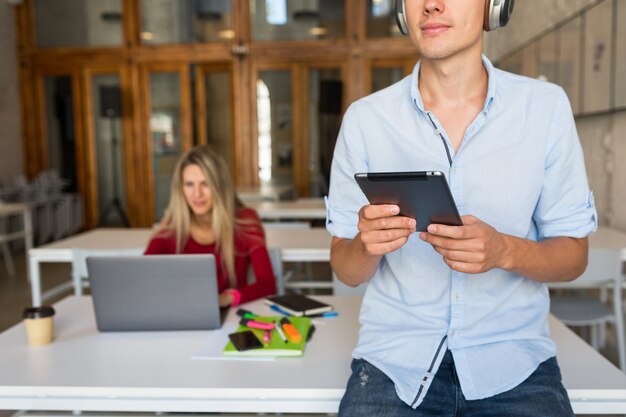 Hombre joven con tableta, escuchando música en auriculares