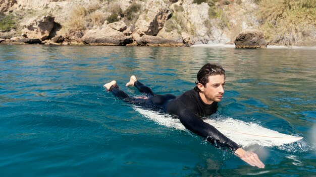 Hombre joven de tiro completo en tabla de surf