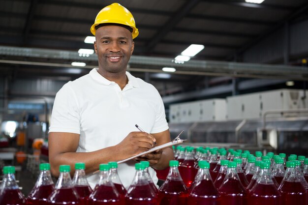 Hombre joven trabajador señalando en la fábrica de jugos