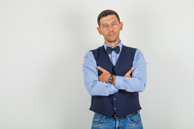 Foto gratuita hombre joven en traje, jeans de pie con los brazos cruzados