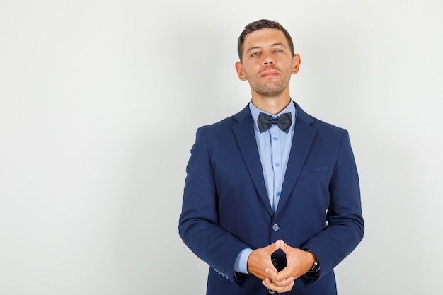 Foto gratuita hombre joven en traje manteniendo las manos cruzadas y mirando confiado