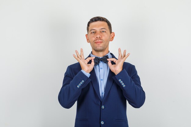 Hombre joven en traje mostrando gesto ok y mirando complacido