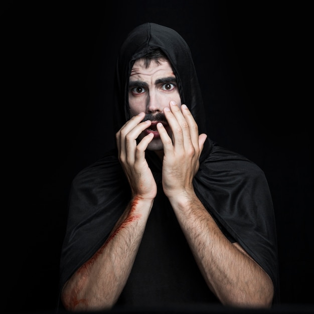 Hombre joven en traje negro de Halloween posando en estudio