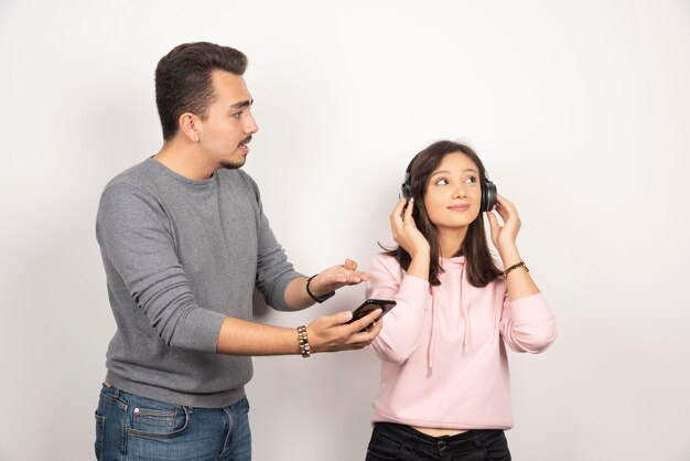 Hombre joven tratando de llegar a la mujer para mirar su teléfono.