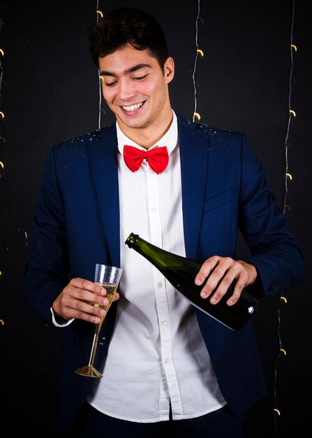 Hombre joven vertiendo champán en copa