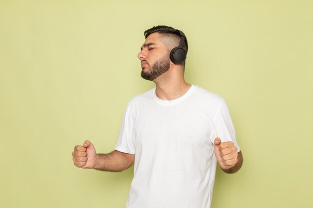 Un hombre joven de vista frontal en camiseta blanca escuchando música