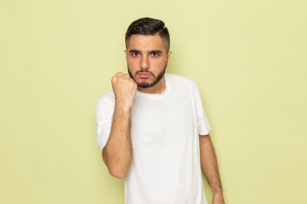 Un hombre joven de vista frontal en camiseta blanca mostrando su puño