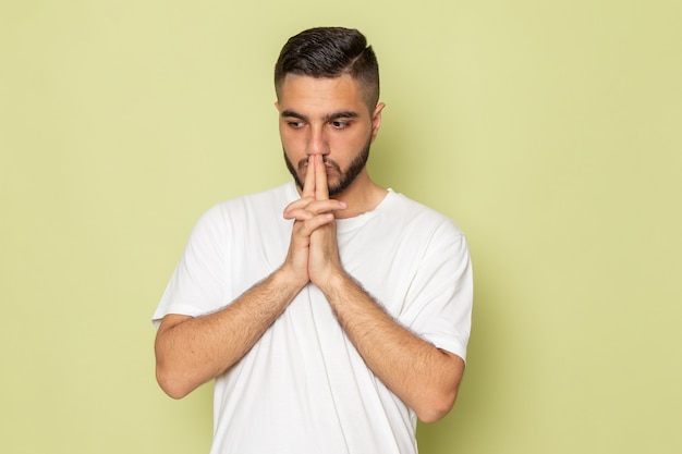 Un hombre joven de vista frontal en camiseta blanca pensando