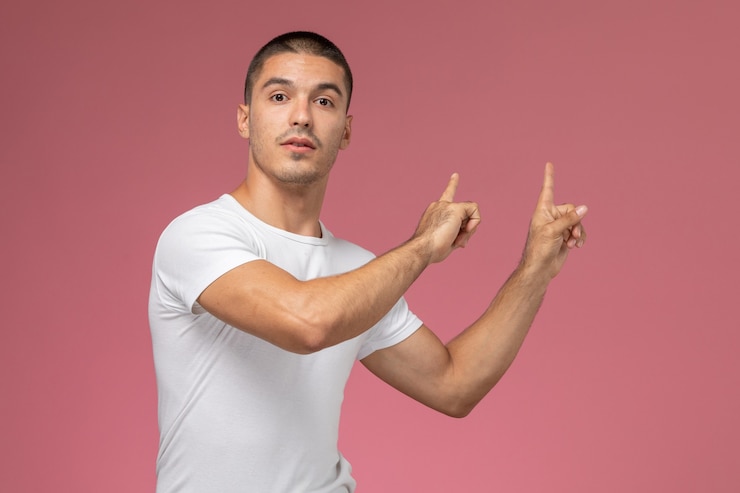 Foto gratuito hombre joven de vista frontal en camiseta blanca posando con los dedos levantados sobre el fondo rosa