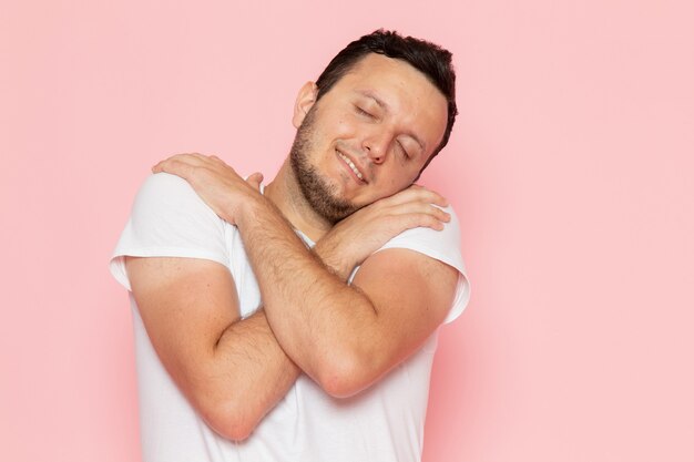 Un hombre joven de vista frontal en camiseta blanca posando con dulce expresión de dormir