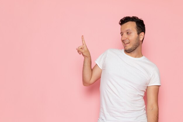 Un hombre joven de vista frontal en camiseta blanca posando con expresión divertida