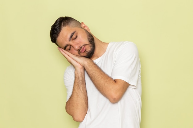 Un hombre joven de vista frontal en camiseta blanca en pose para dormir