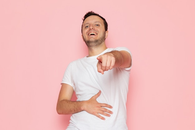 Un hombre joven de vista frontal en camiseta blanca riendo a carcajadas