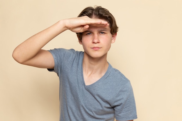 Foto gratuita un hombre joven de vista frontal en camiseta gris mirando a lo lejos