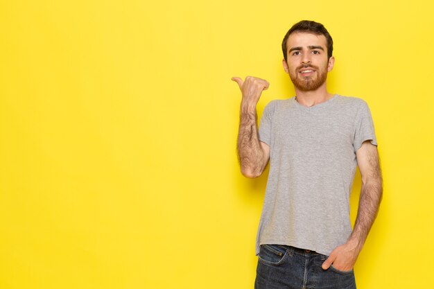 Un hombre joven de vista frontal en camiseta gris en la pared amarilla hombre color modelo emoción ropa