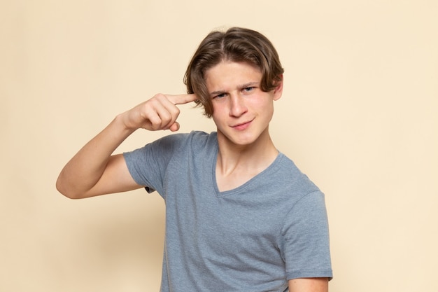 Un hombre joven de vista frontal en camiseta gris posando con expresión