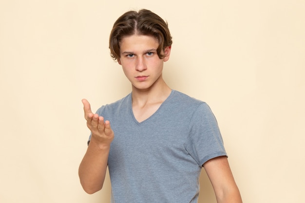 Un hombre joven de vista frontal en camiseta gris posando con gestos