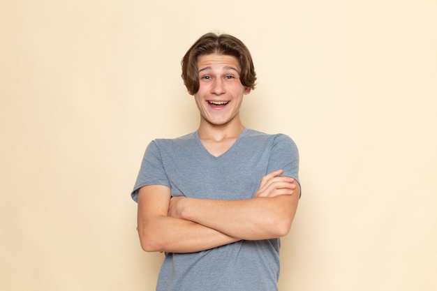 Un hombre joven de vista frontal en camiseta gris posando con risa