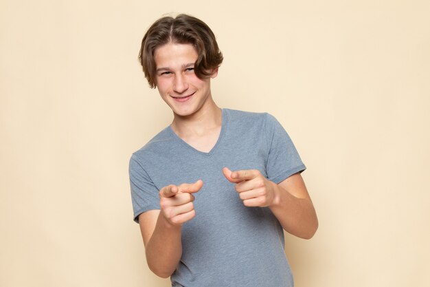 Un hombre joven de vista frontal en camiseta gris posando con una sonrisa