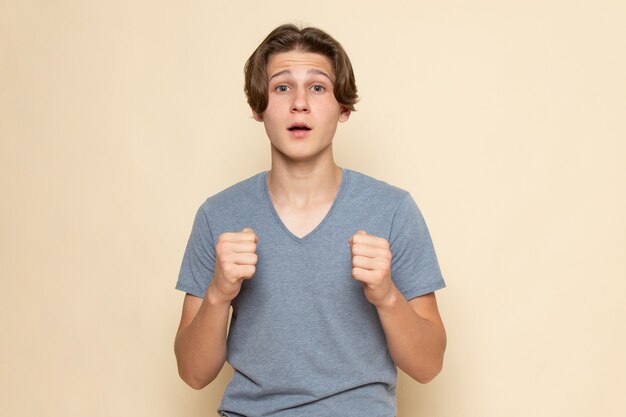 Un hombre joven de vista frontal en camiseta gris posando