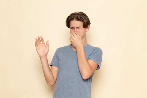 Un hombre joven de vista frontal en camiseta gris que cubre su nariz