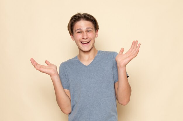 Un hombre joven de vista frontal en camiseta gris riendo de buen humor