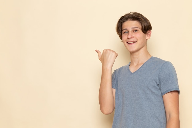 Foto gratuita un hombre joven de vista frontal en camiseta gris señalando y sonriendo