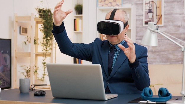 Foto gratuita hombre jubilado que experimenta la realidad virtual con auriculares vr en la sala de estar. taza de café sobre la mesa.