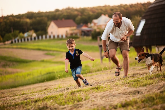 El hombre juega con su hijo y un perro en el campo