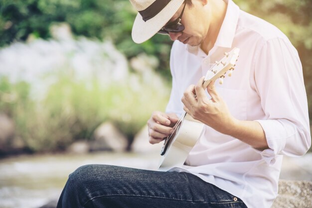 Hombre juega ukelele nuevo al rio.