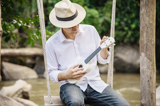 Hombre juega ukelele nuevo al rio.