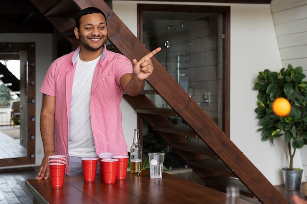 Hombre jugando al beer pong en una fiesta interior