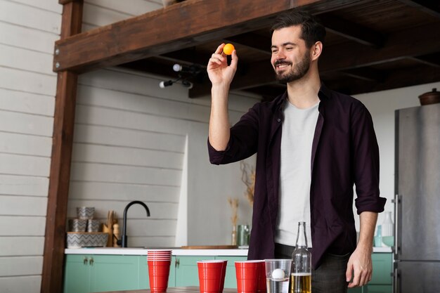 Hombre jugando al beer pong en una fiesta interior