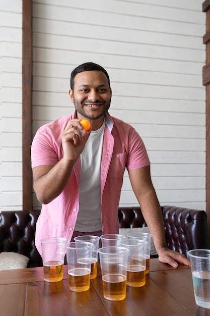 Hombre jugando al beer pong en una fiesta interior