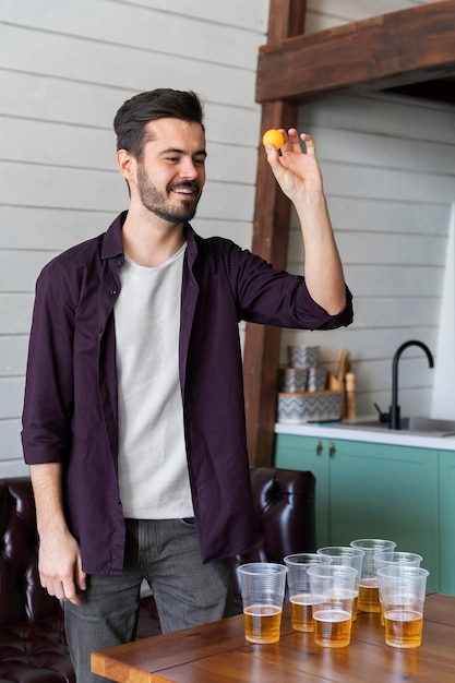 Hombre jugando al beer pong en una fiesta interior