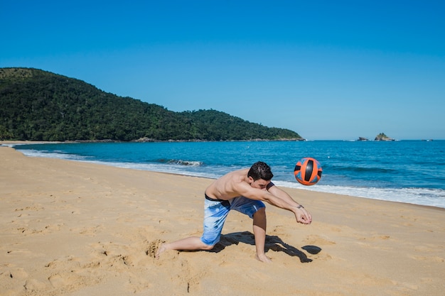 Hombre jugando al voleibol en la orilla