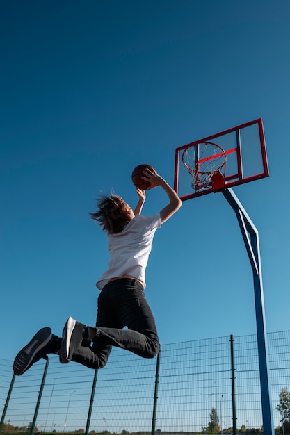 Foto gratuita hombre jugando baloncesto al aire libre ángulo bajo